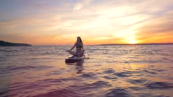 Nő pihentető egy szörfdeszka. Egy nő ül egyedül az óceán ő különleges tábla. — Stock videók