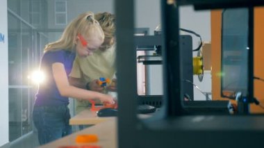 3D yazdırma servisiyle çalışmak çocuklar. Erkek ve kız bir bilim laboratuvar baskı donanımları ile çalışma.