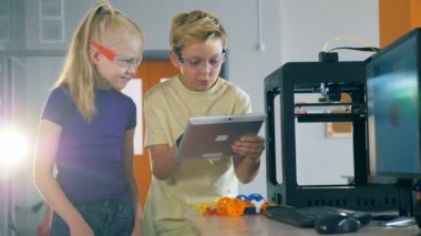 İki öğrenciler bir 3d printerlere harcama maddeler ve tablet deneme. 4k.