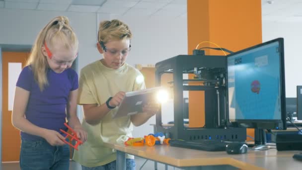 Um menino e uma menina trabalham em um laboratório inventando robô impresso 3d . — Vídeo de Stock