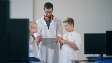 Çocuk ve bir öğretmen, bir laboratuvar odaya yeni baskılı plastik modelleri arıyorsunuz standı.