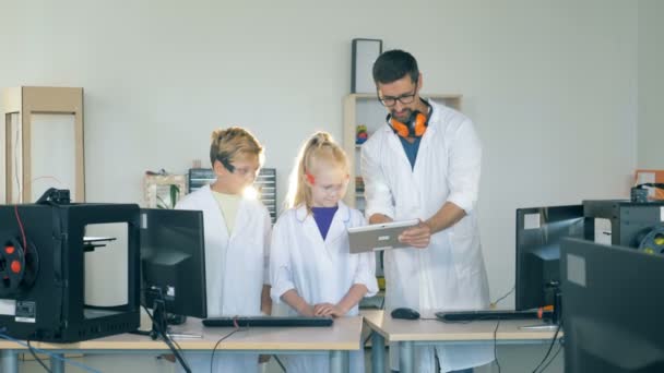 Niños estudiando tecnología moderna en un laboratorio con un profesor de escuela. 4K . — Vídeo de stock