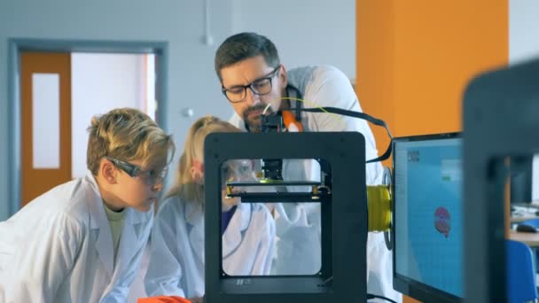 Professor explica crianças processo de impressão 3D em um laboratório . — Vídeo de Stock