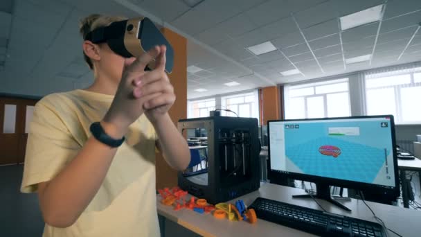 年轻男孩使用虚拟现实耳机在3d 打印机上打印工程机器人部件. — 图库视频影像