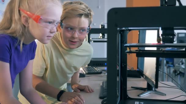 Praca z drukarka 3d dla dzieci. Chłopak i dziewczyna pracuje w laboratorium nauki z 3d sprzętu poligraficznego. — Wideo stockowe