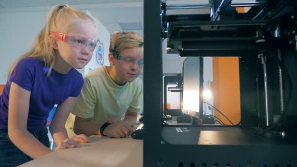 Nadšený školní děti pomocí tří dimenzionální tiskárnu pro tvorbu 3d tištěné robota. — Stock video