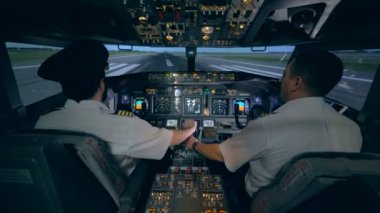 Erkek pilot uçak simülatörü denetlemek için onun stajyer yardım ediyor. Modern yolcu uçak kabin iç.