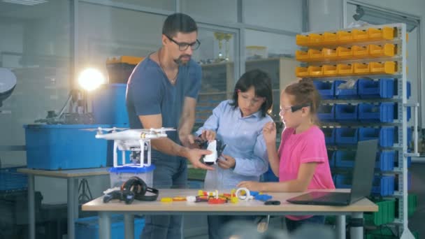 El profesor masculino explica a los niños de la escuela, a los alumnos cómo funciona el helicóptero teledirigido, aicraft. 4K . — Vídeo de stock