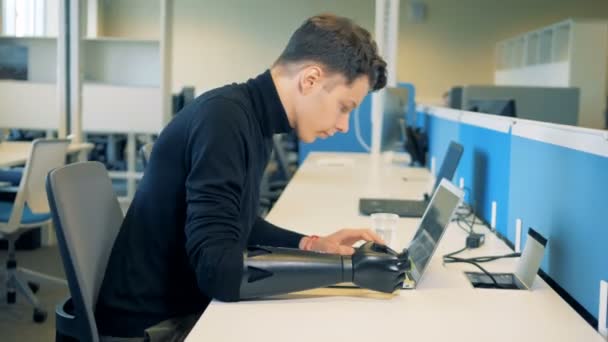 Hombre discapacitado se sienta en una mesa con un ordenador portátil, vista lateral . — Vídeos de Stock