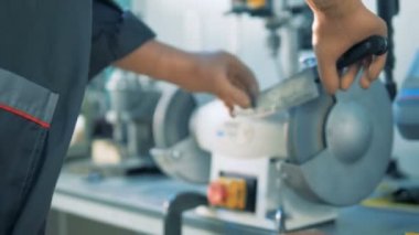 Protez elleri olan bir adam bir metal bıçak keskinleştirir, yakın çekim.