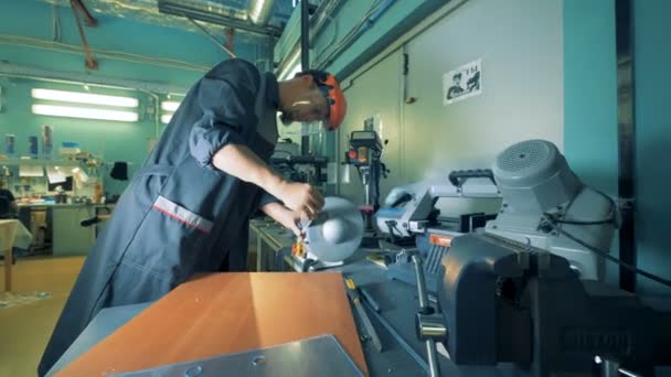 L'homme en casque et uniforme travaille avec des mains prothétiques dans une pièce. 4K . — Video