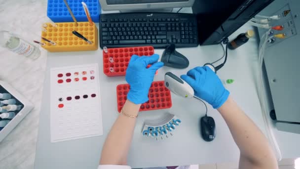 Test tubes with blood are getting scanned by a female lab specialist — Stock Video