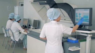 Kadın laboratuvar uzman bir pharmacutical fabrikada bir dokunmatik ekran üzerinde biyokimyasal analyzer manipüle olduğunu.