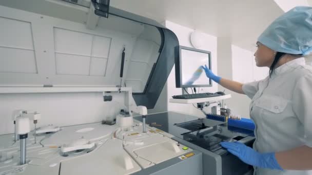 Машина биохимического анализа управляется лаборантом фармацевтического производственного предприятия . — стоковое видео