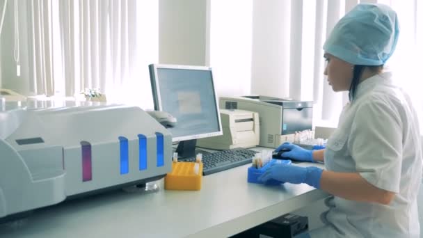 Female laboratory employee is preparing to scan test tubes — Stock Video
