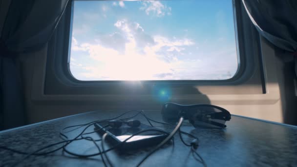 Phone and glasses lay on a table near a train window. — Stock Video