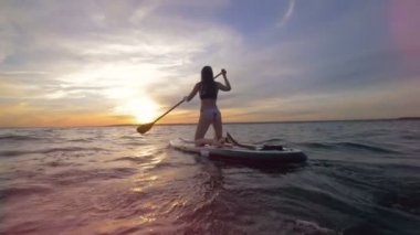 Çekici bir genç bayan paddleboarding oturumu sırasında güneş batana