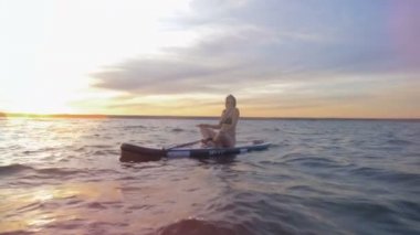 Genç kadın üzerinde pratik yoga açık denizde oturuyordu. Gevşeme kavramı.