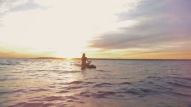 Günbatımı waterscape bir paddleboard üzerinde yüzen bir hanımla. Gevşeme kavramı.