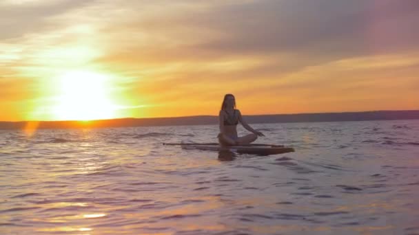 Pratik yoga bir paddleboard üzerinde bir hanımla günbatımı. — Stok video