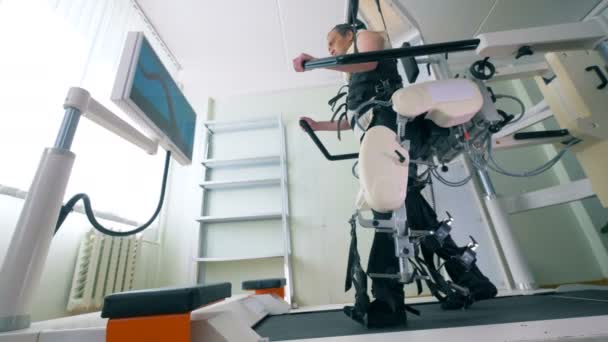 Um paciente caminha em uma pista médica, usando um dispositivo de prótese moderno . — Vídeo de Stock