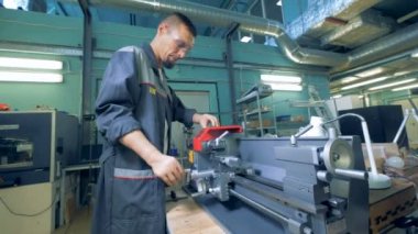 Erkek fabrika çalışan yapay elleriyle bir metal torna ile çalışıyor. 4k