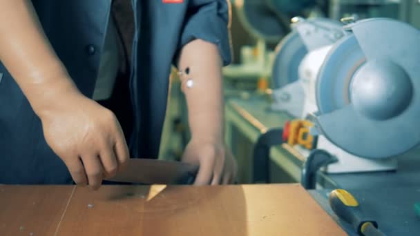 Couteau est aiguisé avec une meule un ouvrier d'usine avec des mains prothétiques — Video