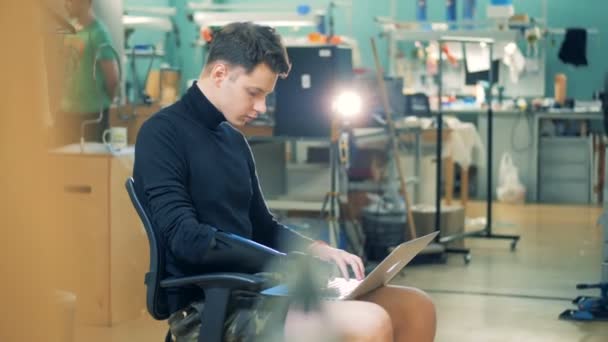 Computer lab with a young man with a prosthetic hand working with a laptop. Cyborg concept. — Stock Video