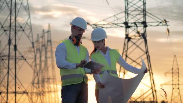 Engenheiros em chapéu duro discutindo projeto elétrico perto da linha de energia . — Vídeo de Stock