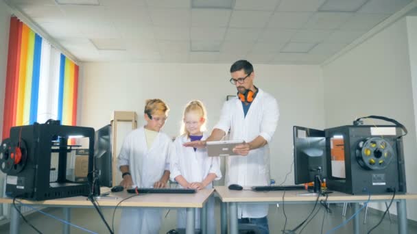 Sala de juegos del laboratorio con un asociado masculino demostrando un experimento a los adolescentes — Vídeos de Stock