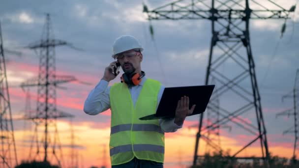 Elektrikář, používání mobilního telefonu v blízkosti na elektrické vedení, elektrické rozvodny. 4k. — Stock video