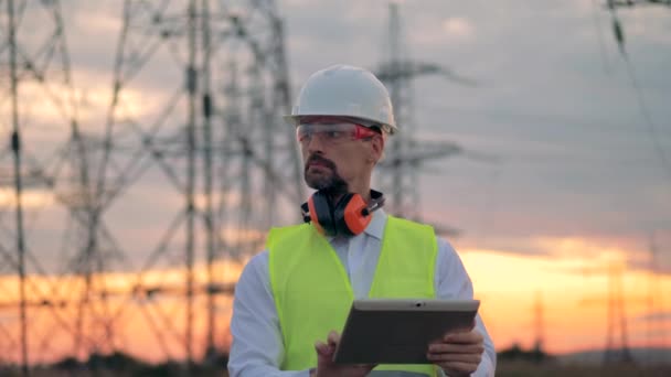 Dělník elektrikář s tabletem v blízkosti elektrického vedení. — Stock video