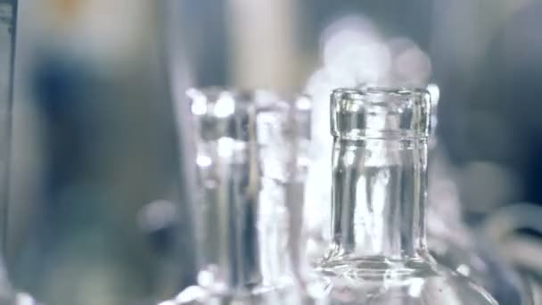 Les bouteilles vides vont dans une rangée sur un convoyeur d'usine. 4K .