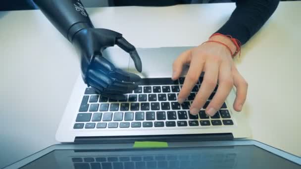 Ein menschlicher Cyborg mit Roboterhand, der an einem Laptop arbeitet, Draufsicht. — Stockvideo