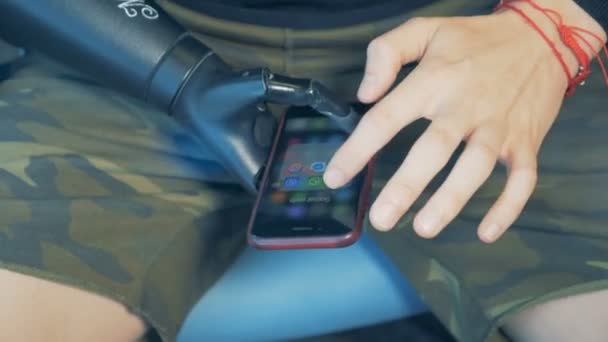 Un uomo disabile, cyborg con protesi bioniche controlla i messaggi telefonici. 4K . — Video Stock