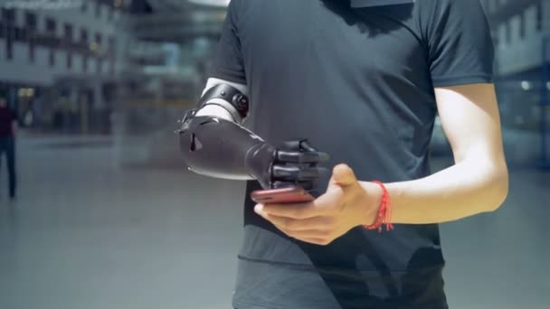 Człowiek z bioniczną ręką protetyczne, patrząc na jego telefon. — Wideo stockowe