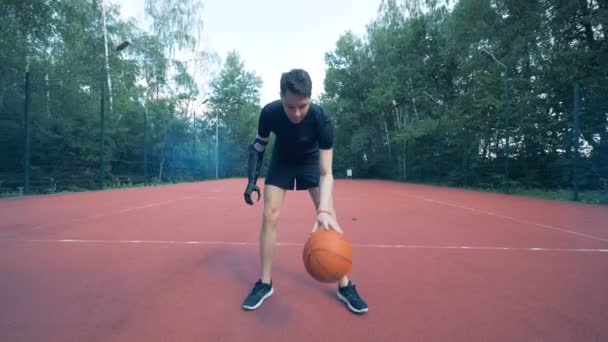 El cyborg humano discapacitado con prótesis biónica juega baloncesto con su brazo artificial. 4K . — Vídeos de Stock