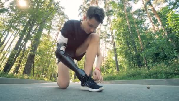 Man ties his sneakers with an artificial arm, close up. Futuristic robotic cyborg arm on a human. — Stock Video