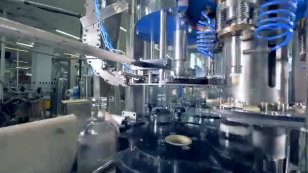 Equipo de fábrica colocando tapas en botellas, de cerca. Equipos industriales automatizados . — Vídeo de stock