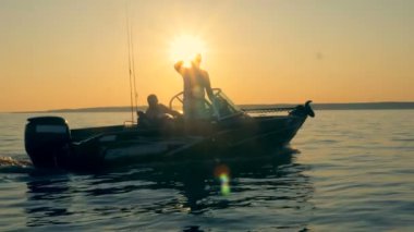 Balıkçılık çubuklar ile birkaç adam bir autoboat güneş ışığı üzerinde yüzen