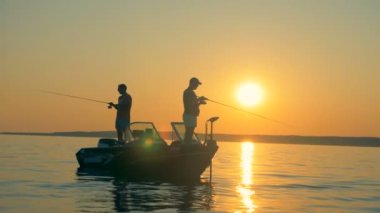 İki balıkçı gündoğumu sırasında bir tekne içinde duran balık yakalamak