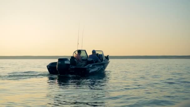 Два человека плывут на моторной лодке через озеро — стоковое видео