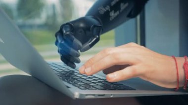 Adam ile bir dizüstü bilgisayar, biyonik el üzerinde çalışıyor. Cyborg kavramı.