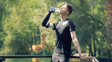 Adam bir şişe yudumlarken yapay eliyle tutar. İnsan robot kolu.