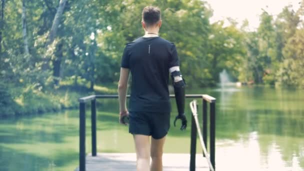 Disabled person near a pond. Human with a robot arm. — Stock Video