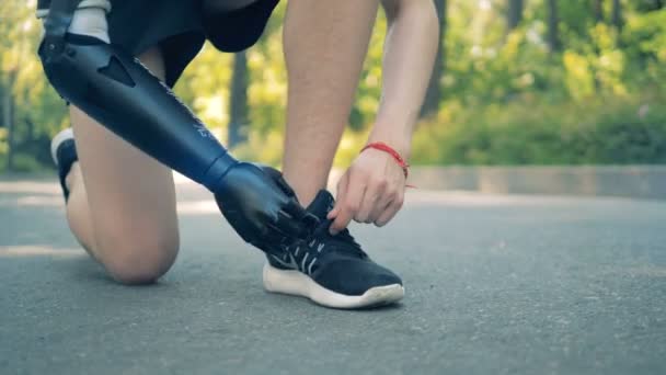 Orang cacat mengikat sepatu kets, close up. Manusia dengan lengan robot . — Stok Video