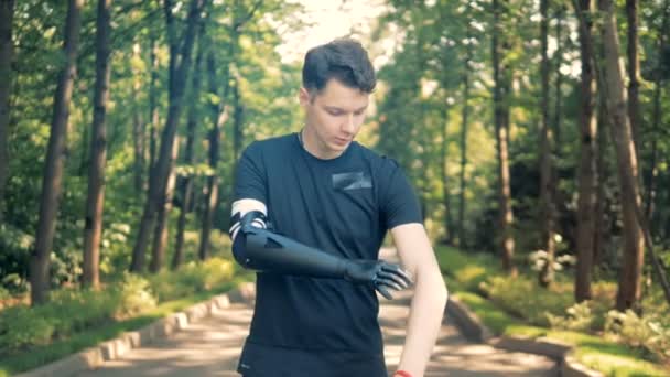 Disabled man with bionic prosthesis stands, crossing his hands. Human with a robot arm. — Stock Video