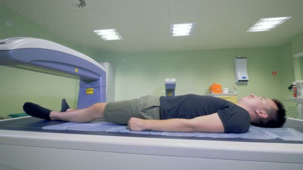 Un patient masculin est scanné par un appareil de radiographie. 4K . — Video