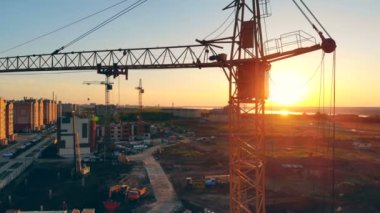 Gün batımı bir arka plan üzerinde inşaat alanında. Bir inşaat sahasında Vinçler.