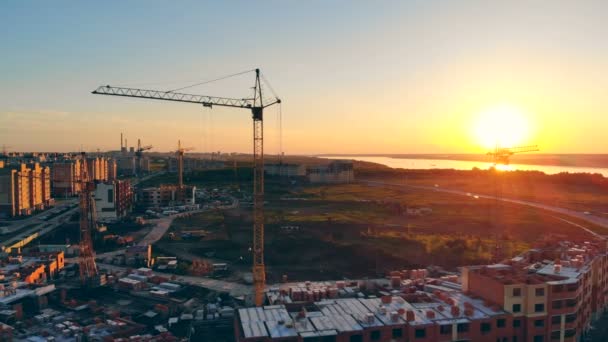 Um canteiro de obras nos arredores. Guindaste de construção ao pôr do sol fundo . — Vídeo de Stock